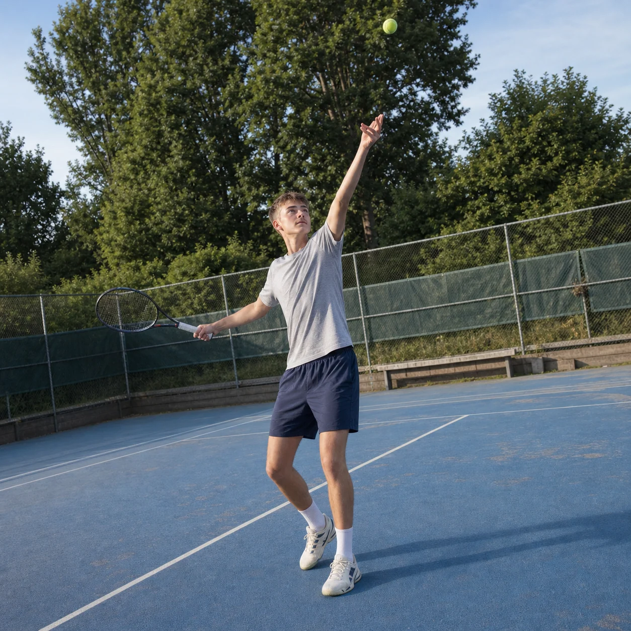 Benjamin beim Tennisaufschlag auf einem blauen Court